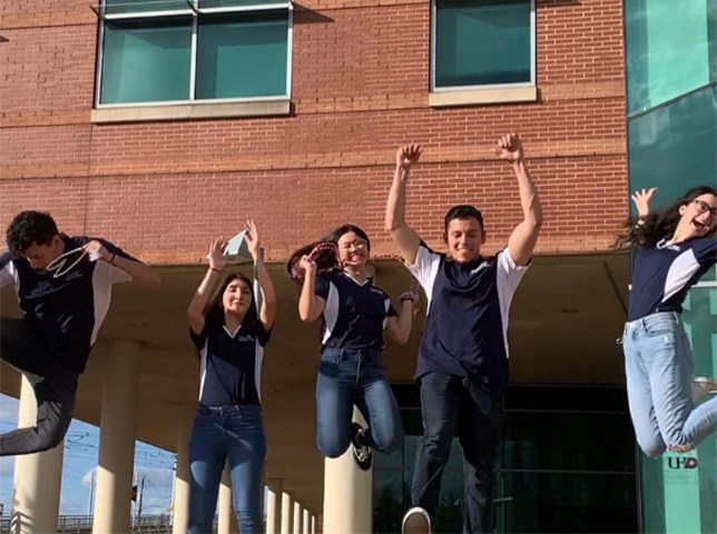Group of students jumping up in front of building