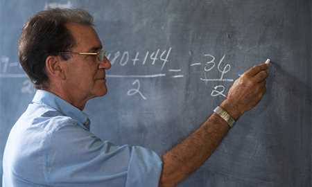 Man solving math equation on chalk board