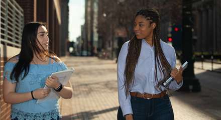 Two female UHD students walking on the sidewalk of downtown Houston
