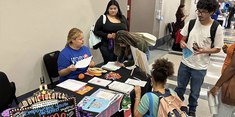 More students with snacks at the Empowered Youth filling out paperwork.